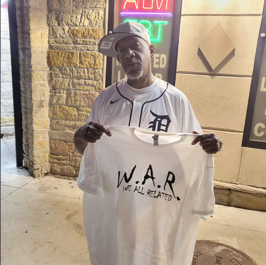 Man wearing a white W.A.R. — We All Related t-shirt